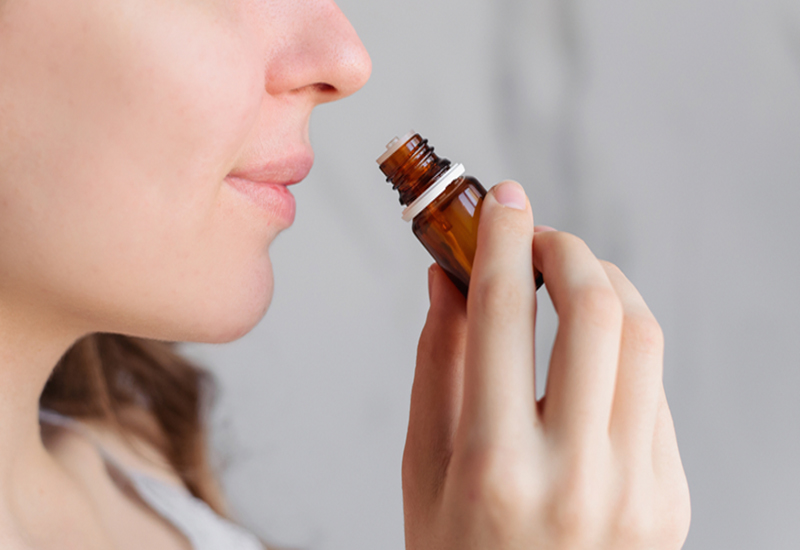 A woman inhaling essential oils directly from the bottle A woman inhaling essential oils directly from the bottle