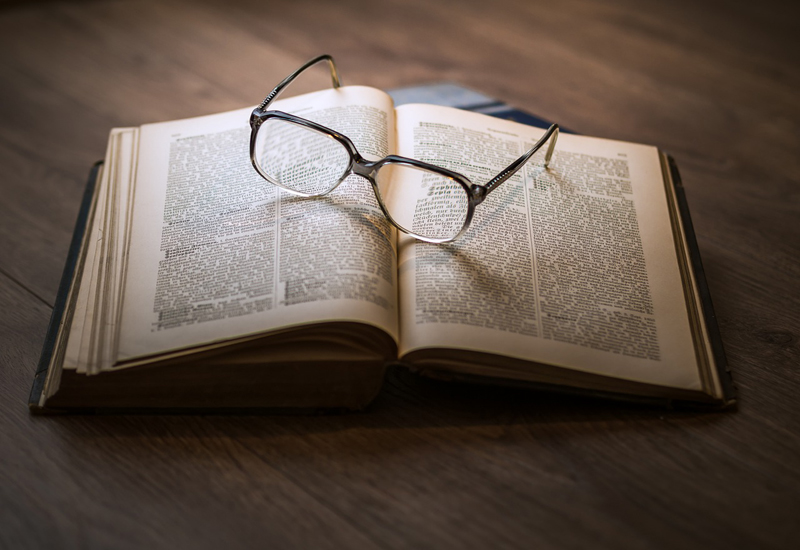 An open book with glasses on it. An open book with glasses on it.
